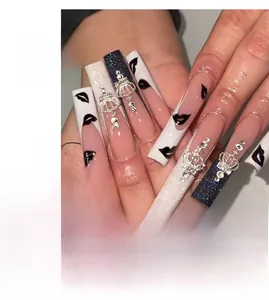 Detailed long coffin nails featuring black lip prints, crown charms, and rhinestones