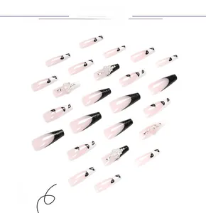 Detail of long ballerina press-on nails with black French tips, lip prints, and silver crowns