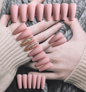 Macro detail of matte pink ballet nails with colorful rhinestones and gold studs