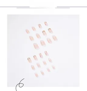 Dettaglio di unghie finte sfumate rosa nude con glitter dorati e motivi a linee bianche