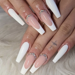 Macro detail of long coffin nails with white French tips and rhinestone accents