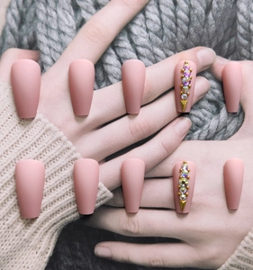 Detailed close-up of matte pink ballet nails with luxury rhinestones and gold studs