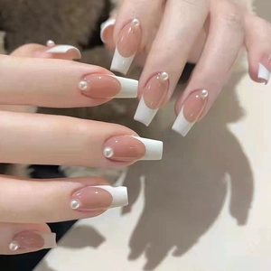 Close-up of long square French press-on nails with nude pink base and pearl detail
