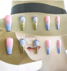 Detail of pink and blue gradient long coffin fake nails with rhinestones and gold foil