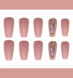 Close-up of matte rose pink coffin nails with iridescent rhinestones and gold accents