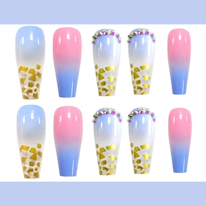 Macro detail of long press-on nails with blue gradient, gold foil, and colorful rhinestones