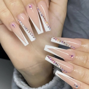 Close-up of long coffin press-on nails with white V-French tips and colorful rhinestones