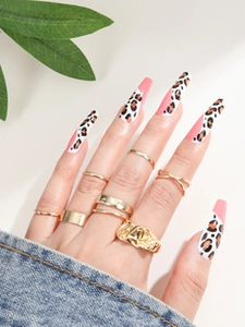 Fashionable leopard print and pink almond press-on nails shown with gold rings