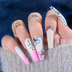 Detail of long coffin nails with pink-blue gradient, hand-painted flowers, and rhinestones