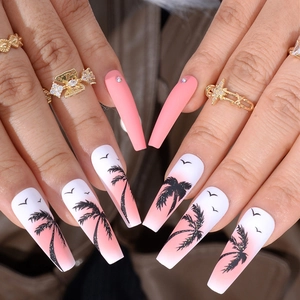 Gros plan d'ongles dégradés roses avec silhouettes noires de palmiers et d'oiseaux
