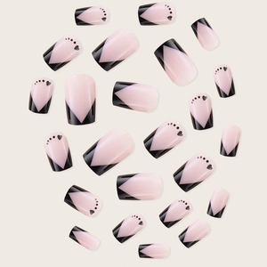 French tip press-on nails with black V-shape design and heart accents on nude base