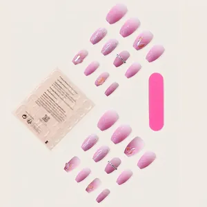 Press-on nail set with pink gradient glitter and rhinestones on a light beige backdrop