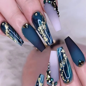 Dark blue marble press-on nails with gold foil and rhinestone accents in coffin shape