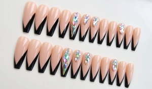 Dettaglio di unghie finte ballerina lunghe con punte francesi nere e strass colorati