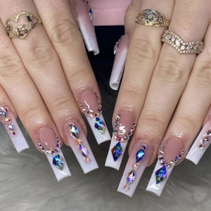 Close-up of long French press-on nails with sparkling rhinestones and crystal charms