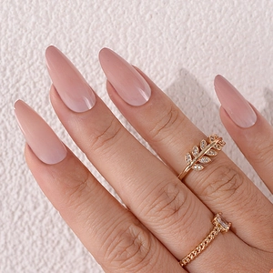 Détail d'ongles amande nus avec bagues délicates en or et feuilles de zircon