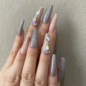 Detail of coffin nails with nude pink base, silver glitter, and iridescent rhinestones