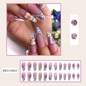 Macro detail of matte stiletto press-on nails with purple floral art and small rhinestones