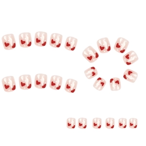 Short pink press-on nails with red heart patterns and white polka dots on white background