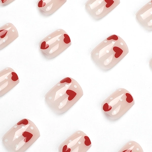 Short square press-on nails with pink translucent base and red heart patterns