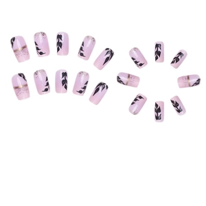 Pink press-on nails with black leaf patterns and gold glitter accents on white background