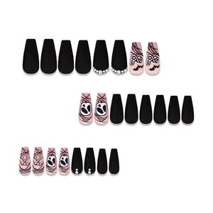 Macro detail of Halloween coffin fake nails with pink skulls and black rhinestone accents