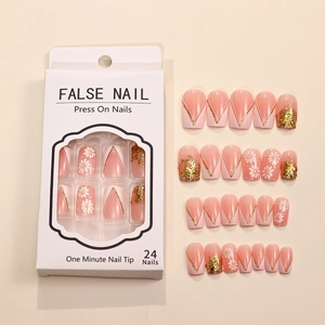 Detail of French false nails with white daisy patterns and gold glitter in a window gift box