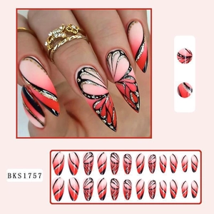 Macro detail of almond press-on nails featuring red butterfly wing patterns and glitter