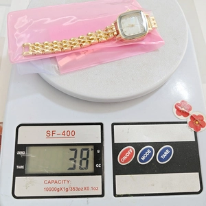 Close-up of lightweight square crystal watch being weighed at 38g on a digital scale