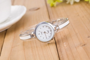 Detailed macro view of a silver-tone quartz bracelet watch on a wooden background