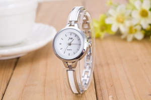 Detailed close-up of a silver quartz watch with enamel links on a wooden surface
