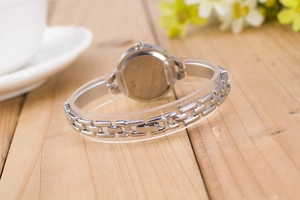 Detail view of the silver mesh chain bracelet and round case back of the quartz watch