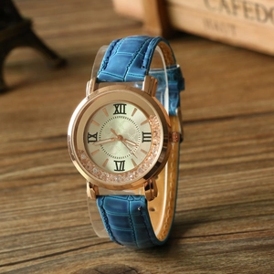 Gros plan sur la montre en or rose avec bracelet en cuir bleu et cristaux flottants