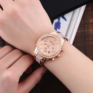 Gros plan d'une montre Genève or rose avec strass au poignet dans un décor de luxe