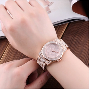 Detail of rose gold quartz watch for women with rhinestones on a dark wood table