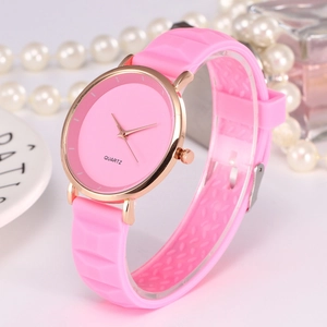 Detailed view of pink silicone watch strap and rose gold dial with perfume bottle background