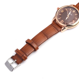Macro view of rose gold quartz watch with brown leather strap and classic dial details