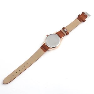 Detail of rose gold case and brown alligator embossed leather strap with buckle