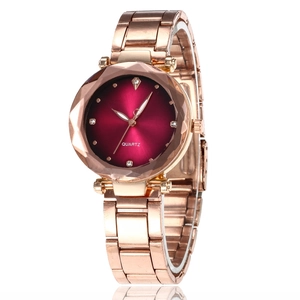 Detail of rose gold quartz watch featuring a faceted crystal bezel and deep red dial