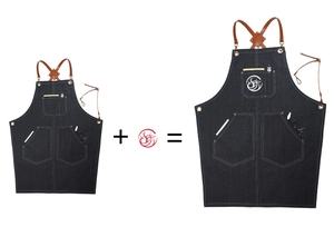 Détail du tablier de travail en denim foncé avec sangles en cuir et impression de logo