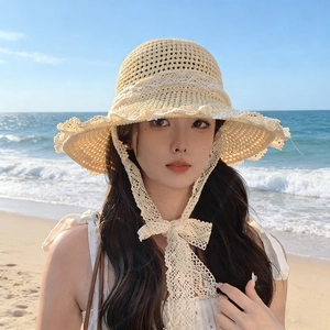 Close-up of beige straw bucket hat featuring white lace trim and straps for summer
