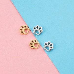 Detailed view of paw print pendants in gold and silver finish on two-tone background
