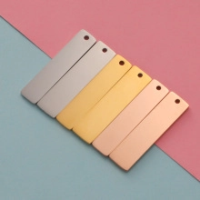 Macro view of rectangular stainless steel pendant charms in silver, gold and rose gold