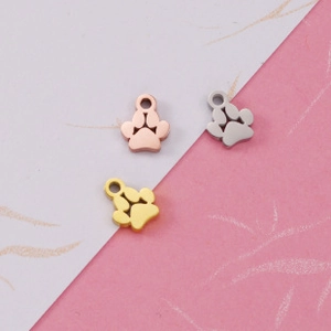 Detailed view of hollow dog paw pendants in gold, rose gold, and silver finishes
