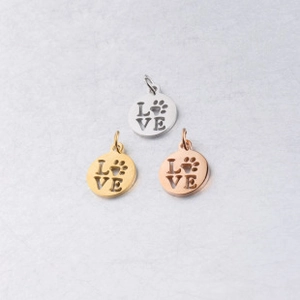 Close-up of circular dog paw and LOVE hollow pendants in silver, gold, and rose gold finishes
