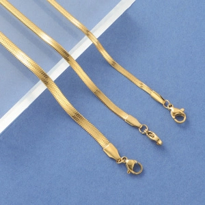 Detailed macro view of three layered golden herringbone chains showing flat woven textures