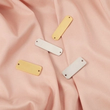 Close-up of golden and silver rectangular stainless steel tags on pink pleated fabric