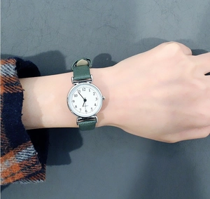 Wrist view of a vintage lady's quartz watch with green leather strap and silver dial