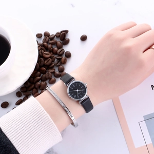 Close-up of minimalist black leather watch with Roman numerals and matching diamond bracelet