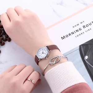Lifestyle shot of a vintage brown leather watch with silver bracelets on a marble background